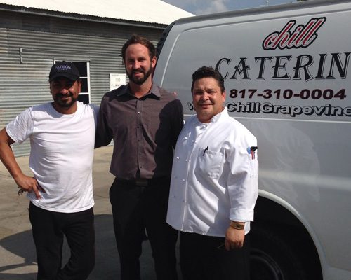 Three men standing in front of a white van.