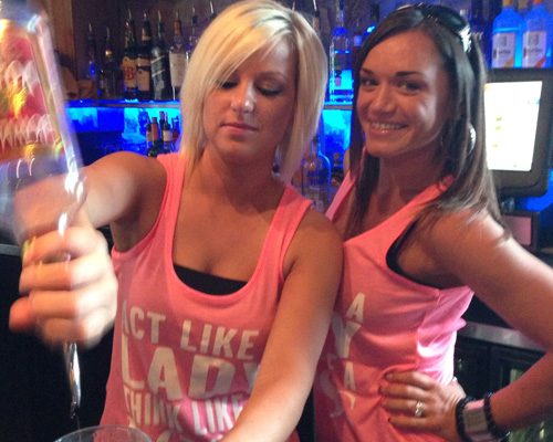 Two women in pink shirts holding a glass of champagne.