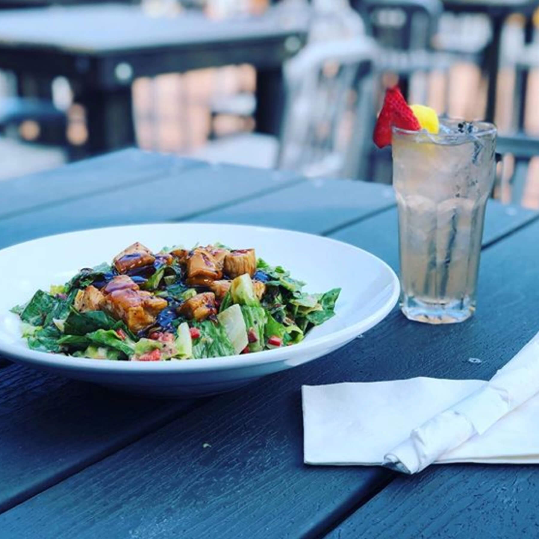 A bowl of salad and a drink on the table.