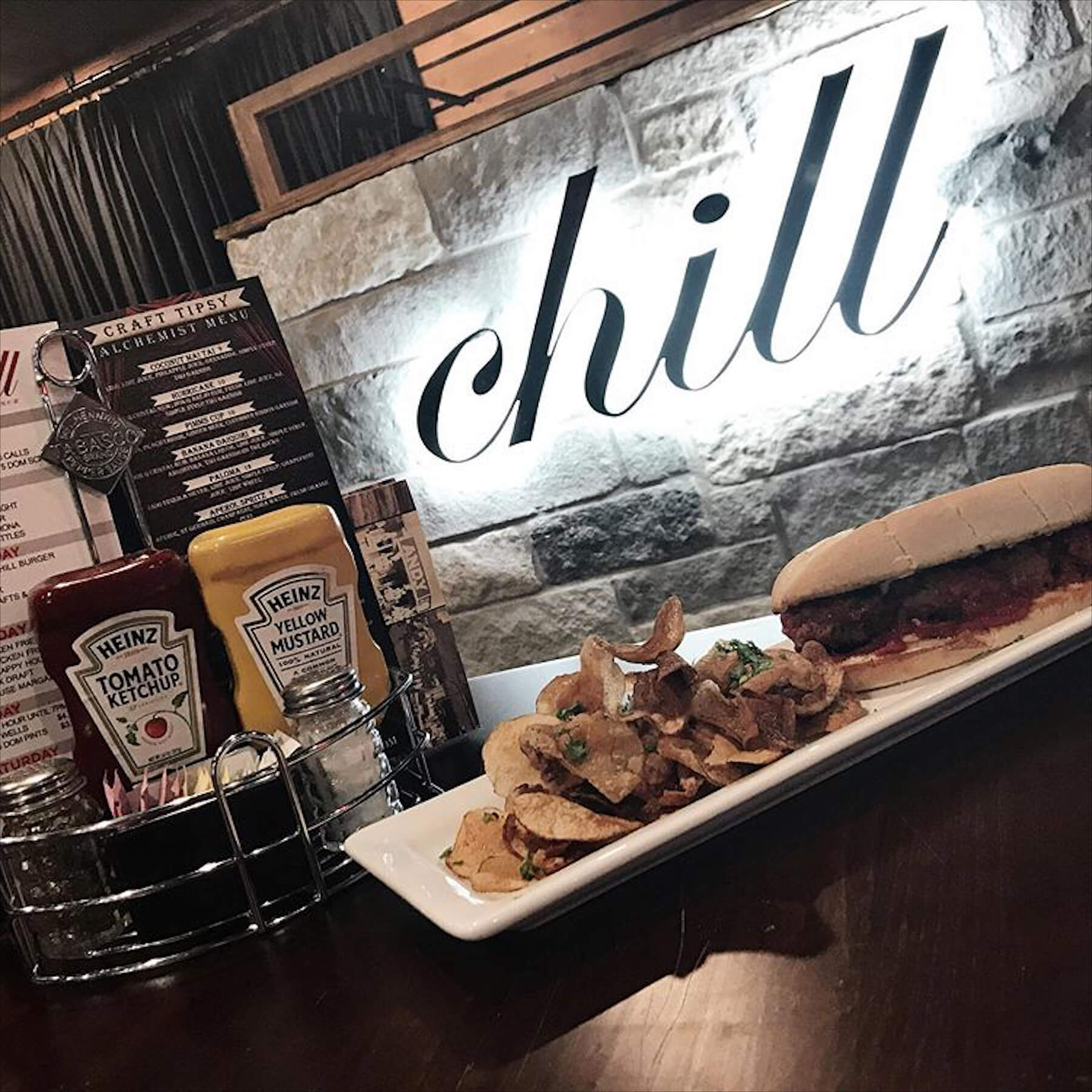 A sandwich and chips on a plate with a sign that says " chill ".